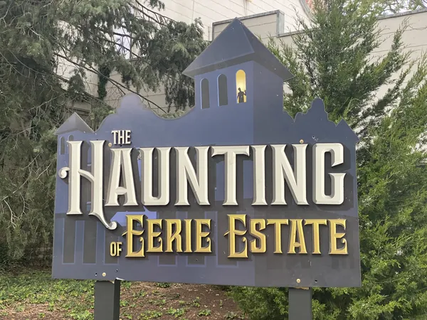 Grey haunted-house-shaped sign reading The Haunting of Eerie Estate at Cedar Point