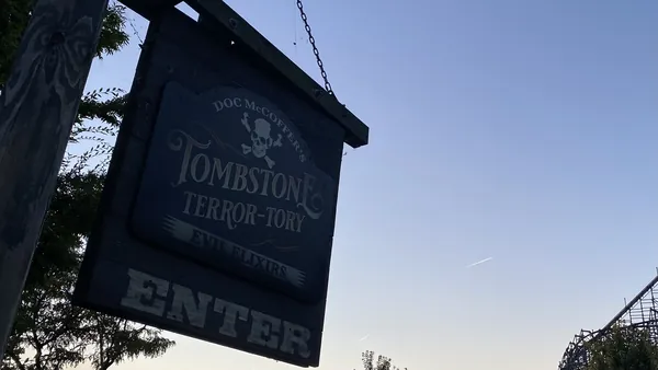 Hanging wooden Tombstone Terrortory sign at Cedar Point silhouetted against a dusk sky