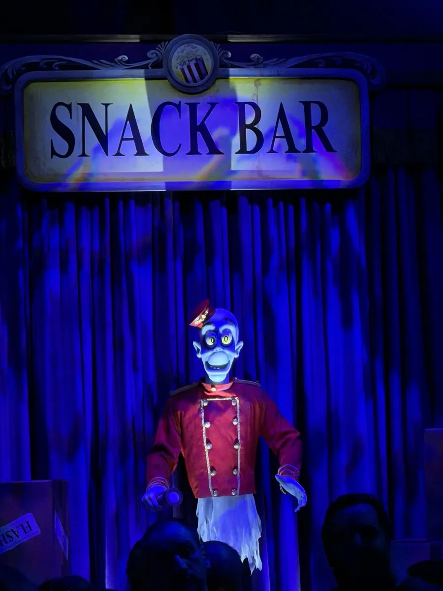 Snack Bar sign and animatronic figure in deep blue light, a callback to the original 1992 Phantom Theater pre-show